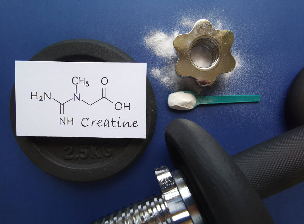 Chemical formula for creatine, a creatine scoop, and a few weights displayed in a gym setting.